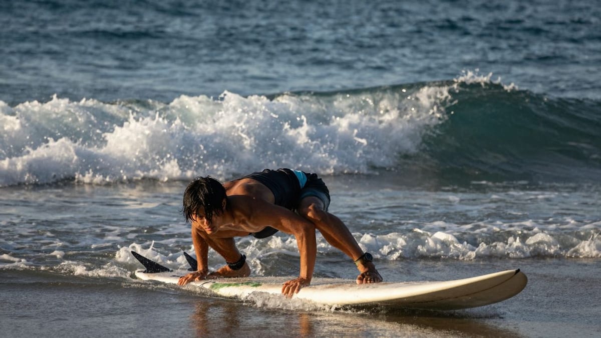Surfer macht Yoga-Übung am Strand bei Sonnenaufgang