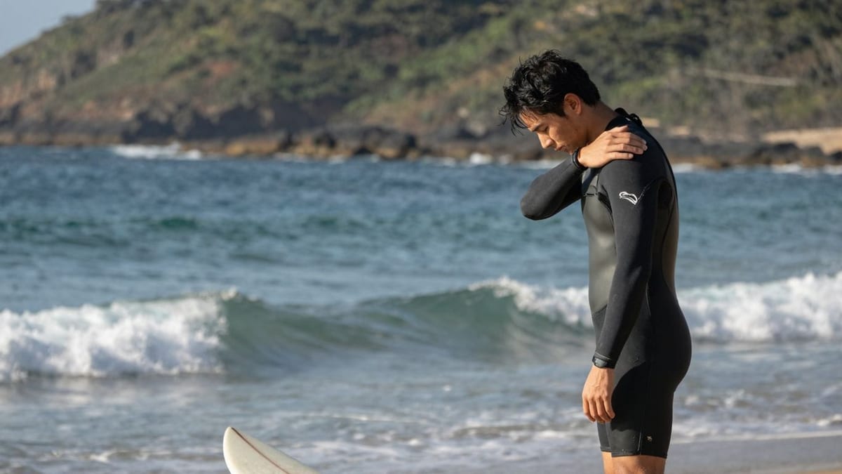 Surfer dehnt sich nach Surfverletzung am Strand.
