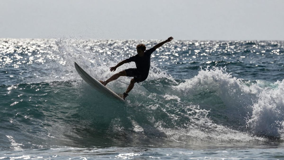 Surfer reitet Welle, spritzendes Wasser, sonniger Strand