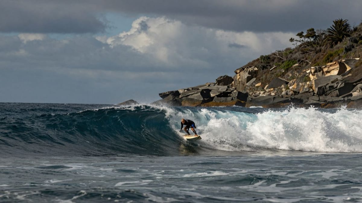 Surfer reitet Welle an felsiger Küste Dänemarks