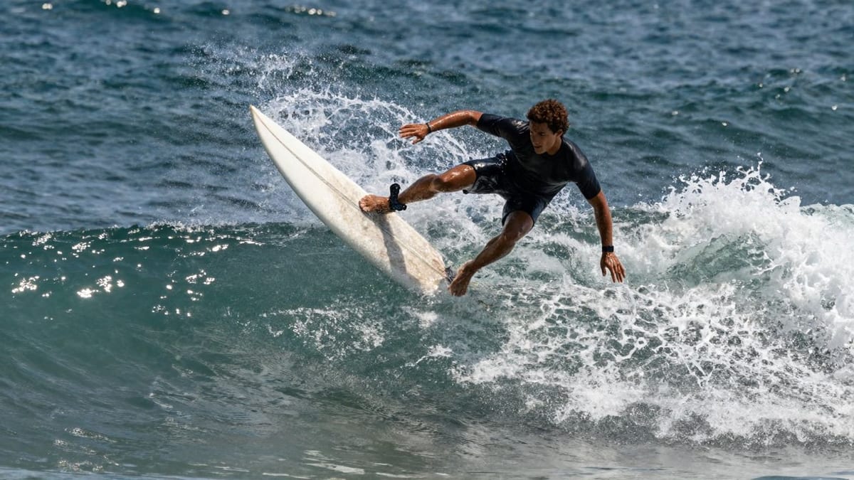 Surfer verliert im Weißwasser das Gleichgewicht, das Brett kippt unter ihm weg